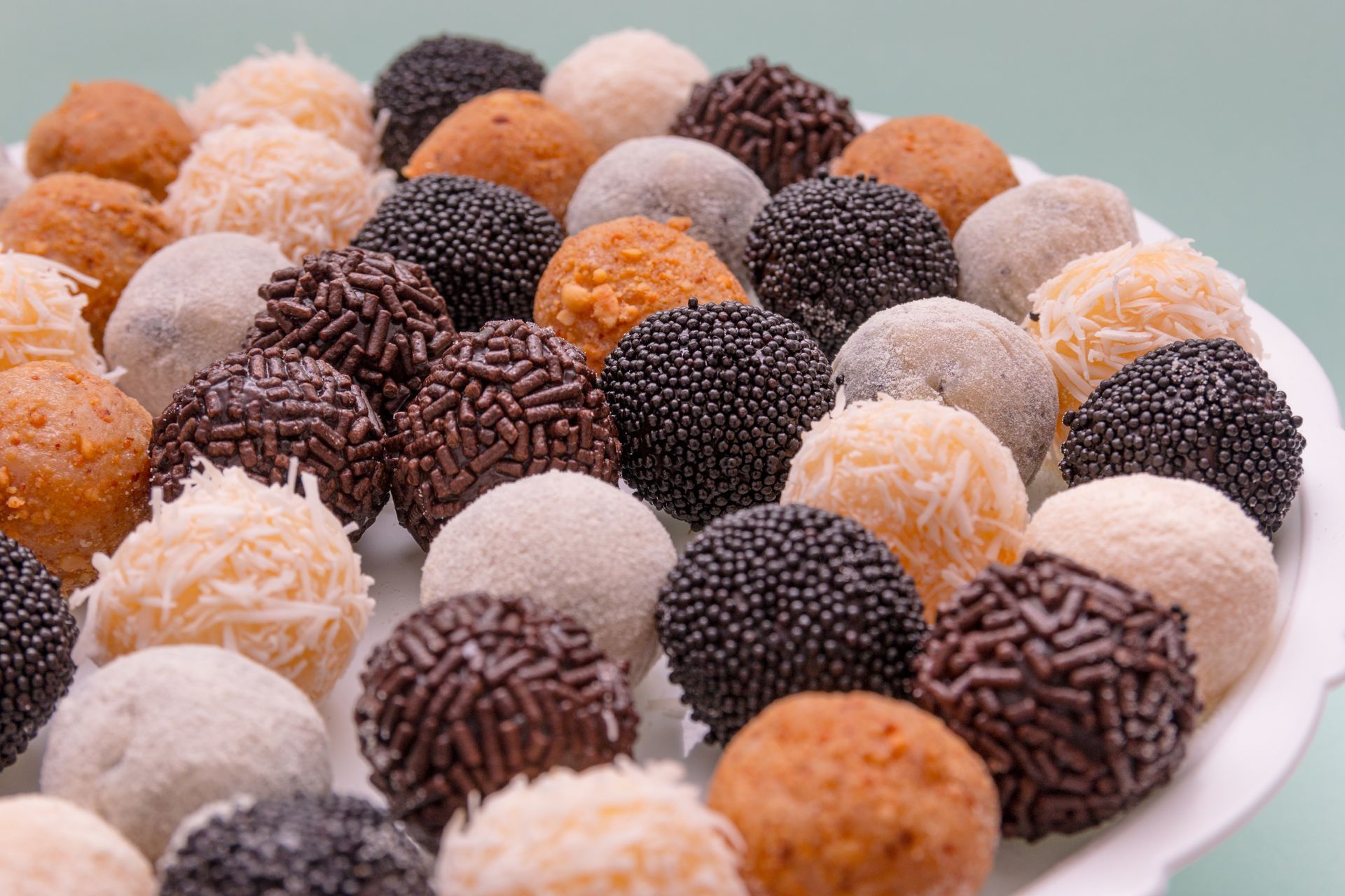 A white plate topped with a variety of balls covered in sprinkles
