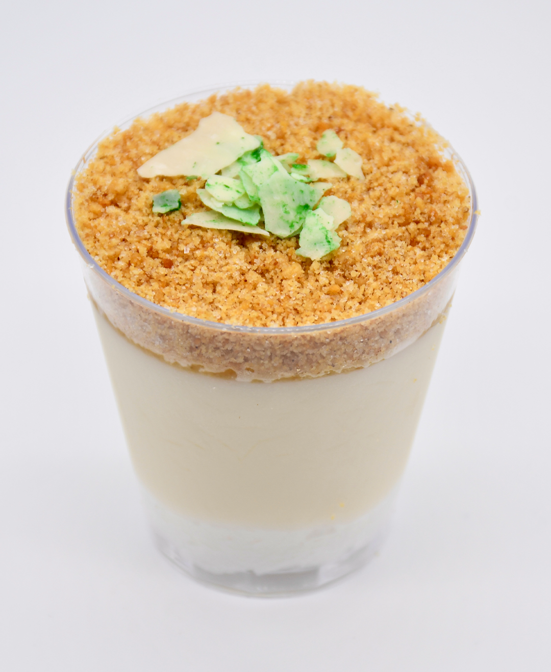 A close up of key lime in a cup with crumbs on top.