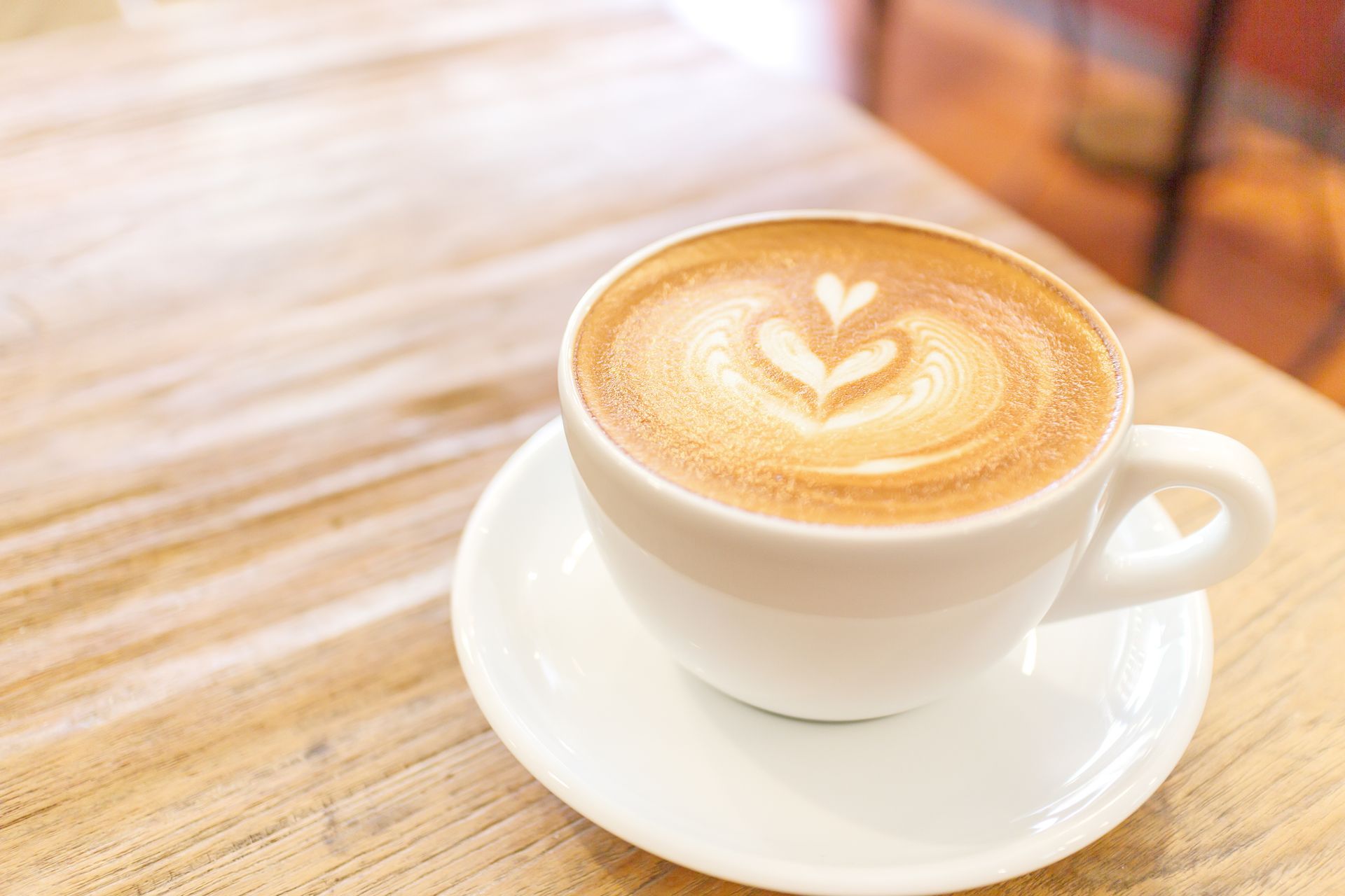 A cup of cappuccino on a saucer on a wooden table.