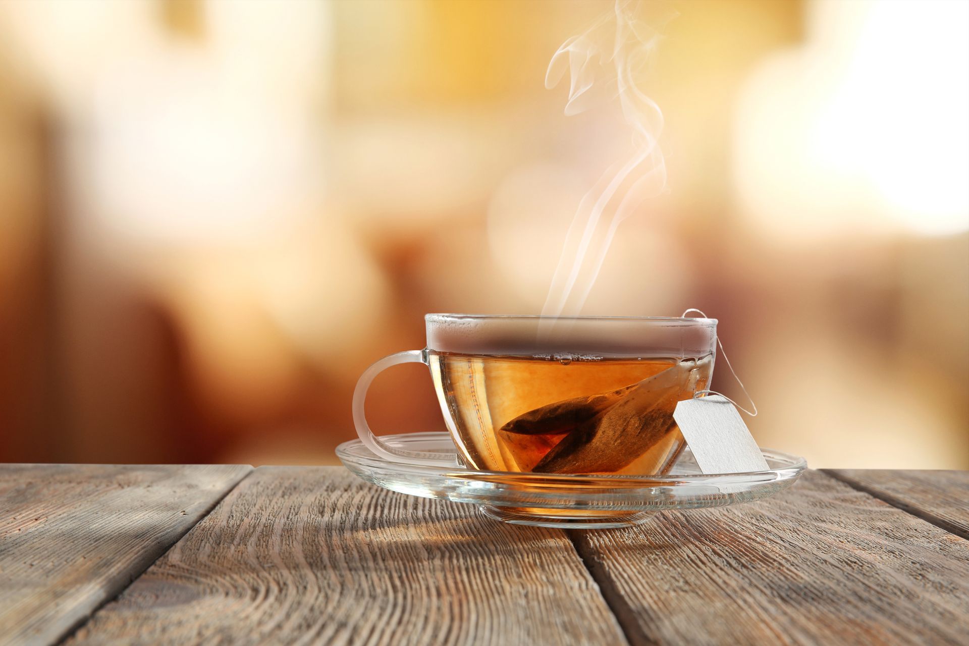 A cup of tea is sitting on a wooden table.