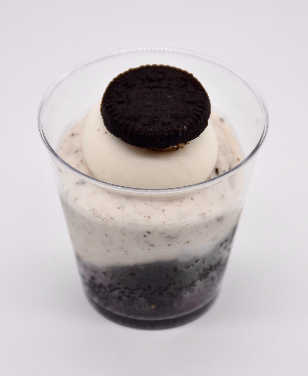 A cup of ice cream with an oreo cookie on top