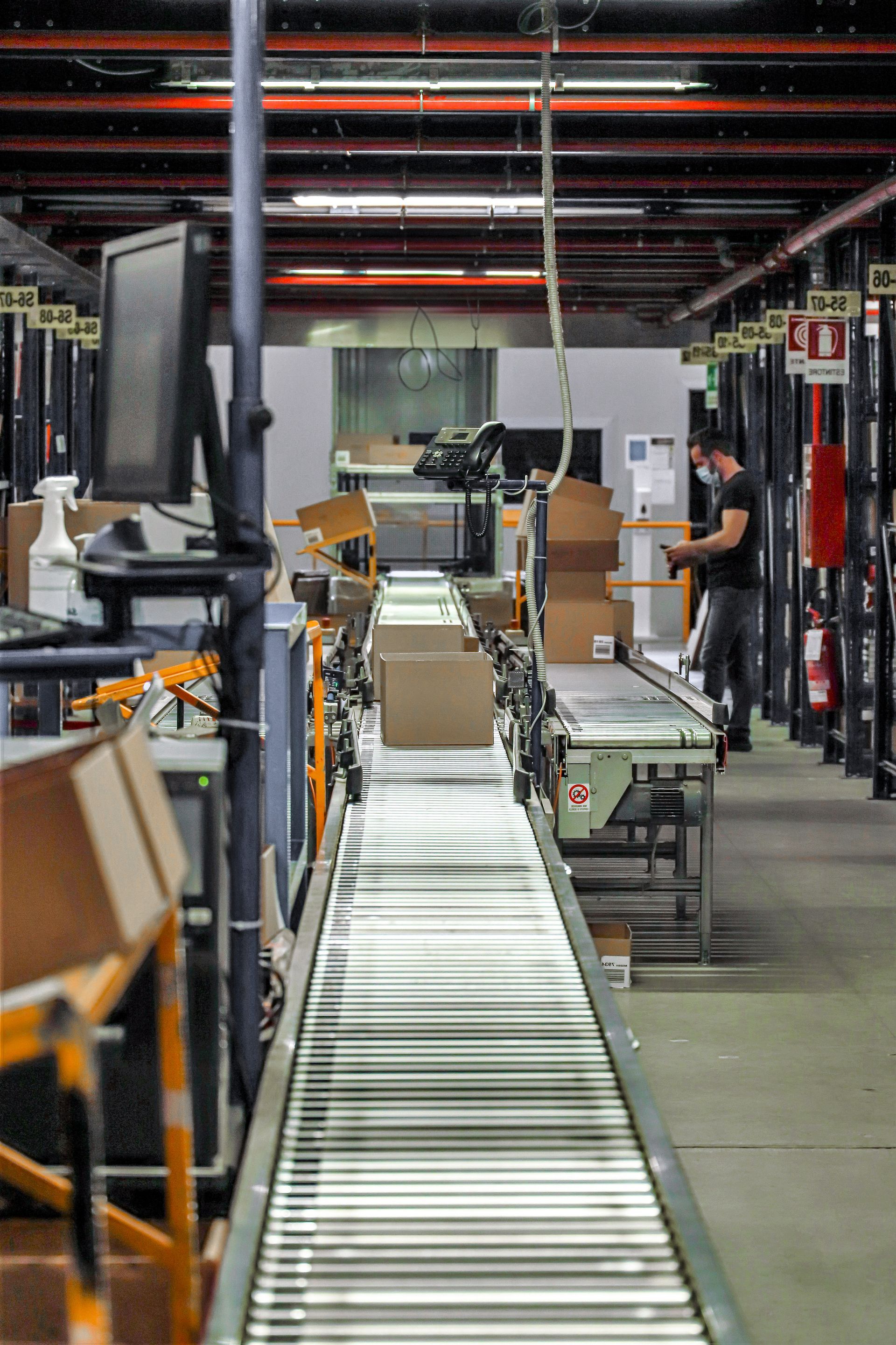Warehouse conveyor line with boxes and workers sorting packages in an industrial facility