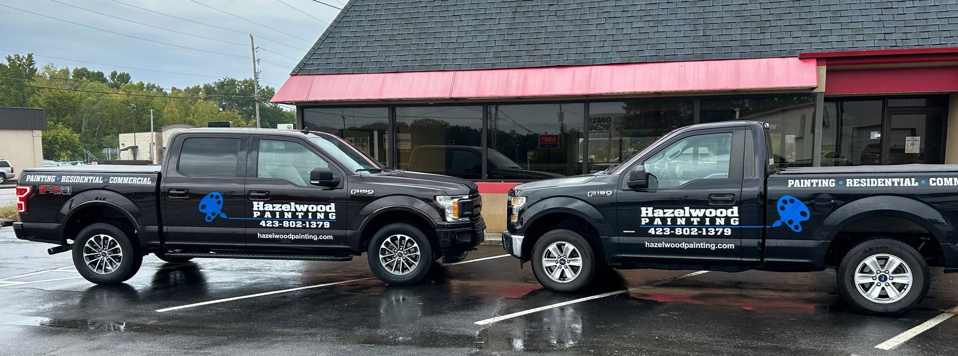 Two black pickup trucks are parked in front of a building.