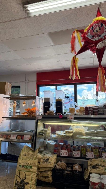 Bakery counter with pastries and drinks, red window trim, and a colorful hanging piñata indoors