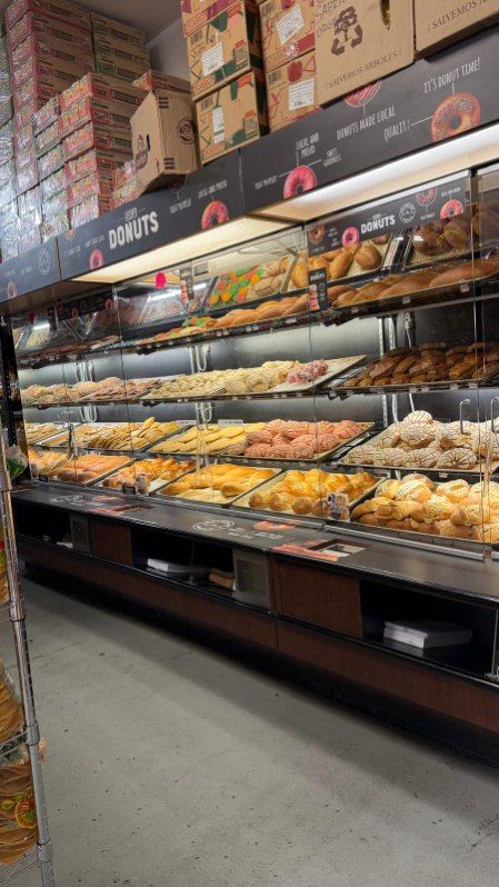 Bakery display case with trays of assorted pastries and bread in a grocery store aisle