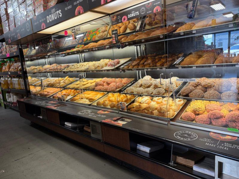Bakery display case filled with assorted donuts and pastries under bright lights
