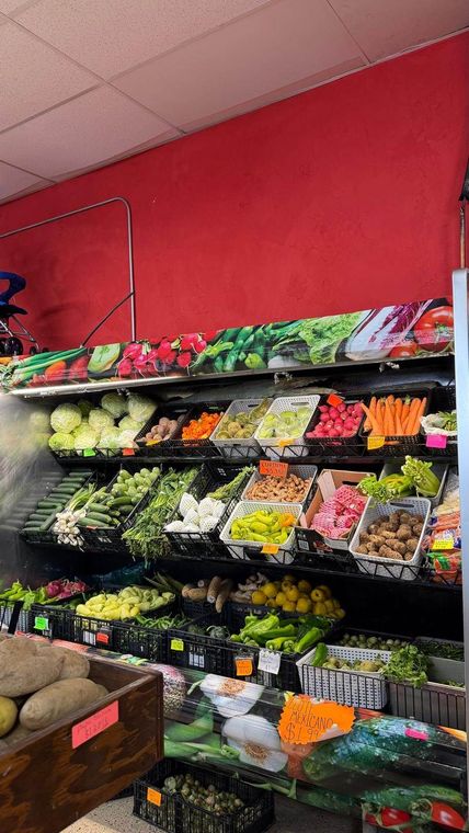 Grocery produce shelf with assorted fruits and vegetables in plastic bins under bright store lighting