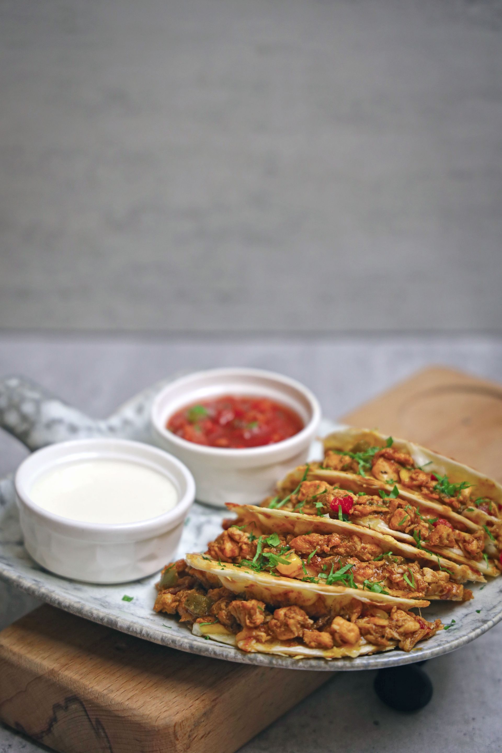 Plate of crispy stuffed bread slices with white dipping sauce and red chutney on a wooden board