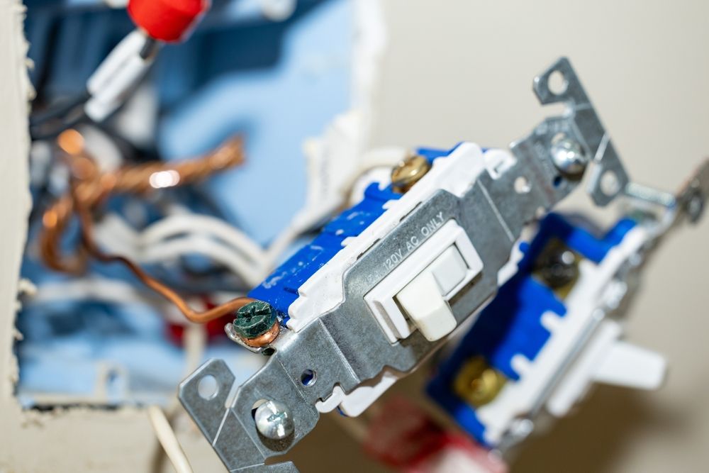 Close-up of an electrical wall switch being installed with exposed wiring and mounting bracket