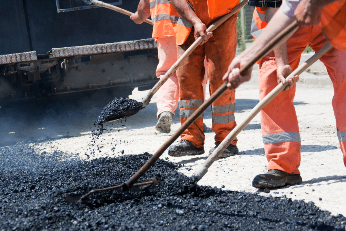 workers in reflective vests using shovels & drill during construction