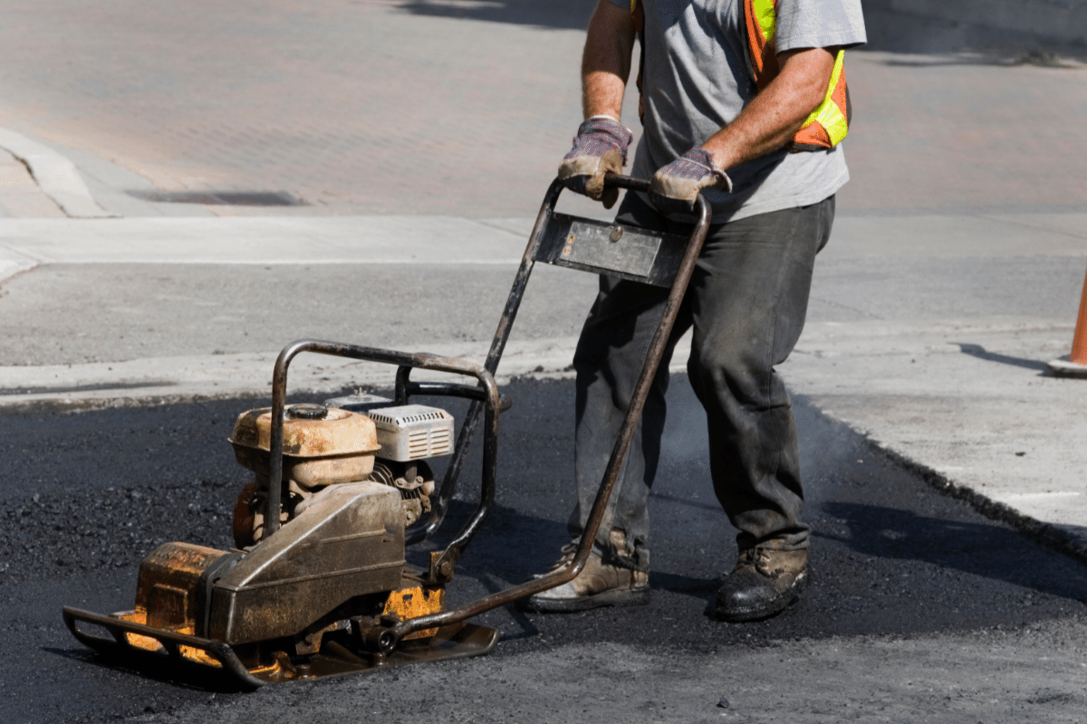worker leveling fresh asphalt on a road construction