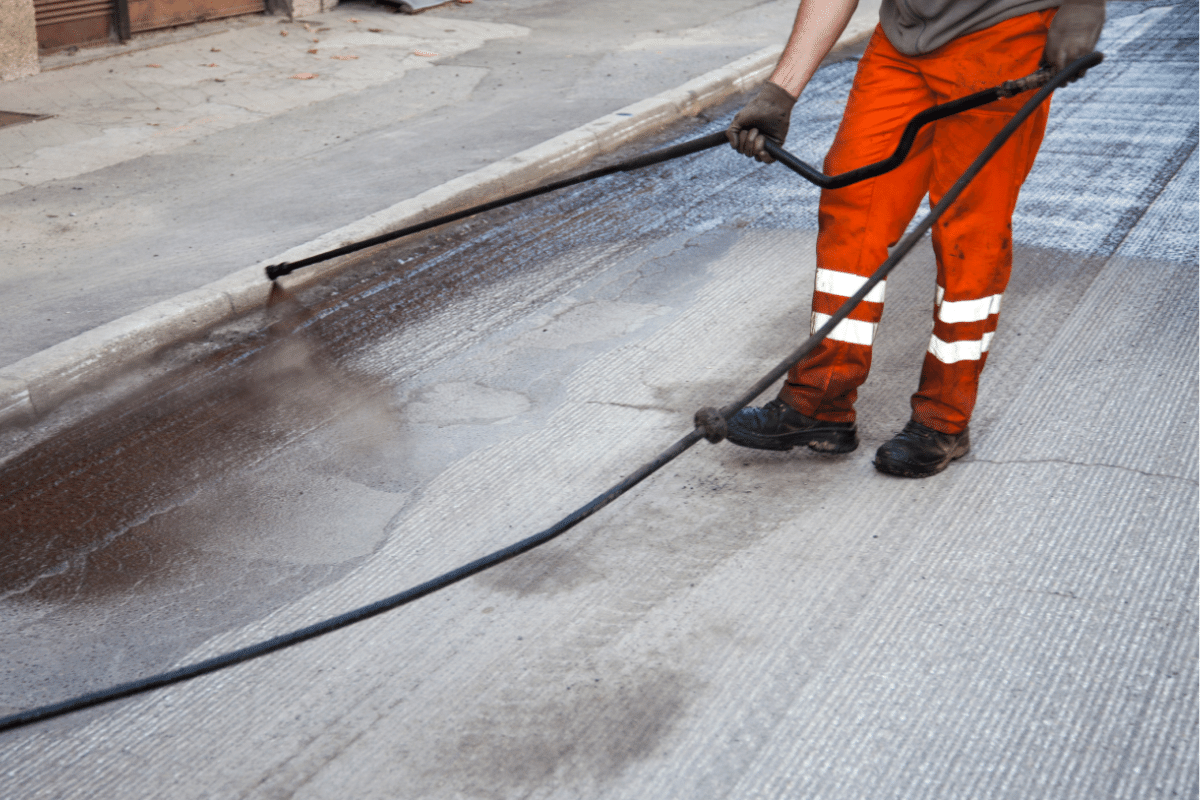 worker leveling fresh asphalt on a road construction