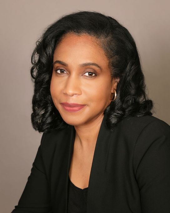 A woman in a black jacket is smiling for the camera