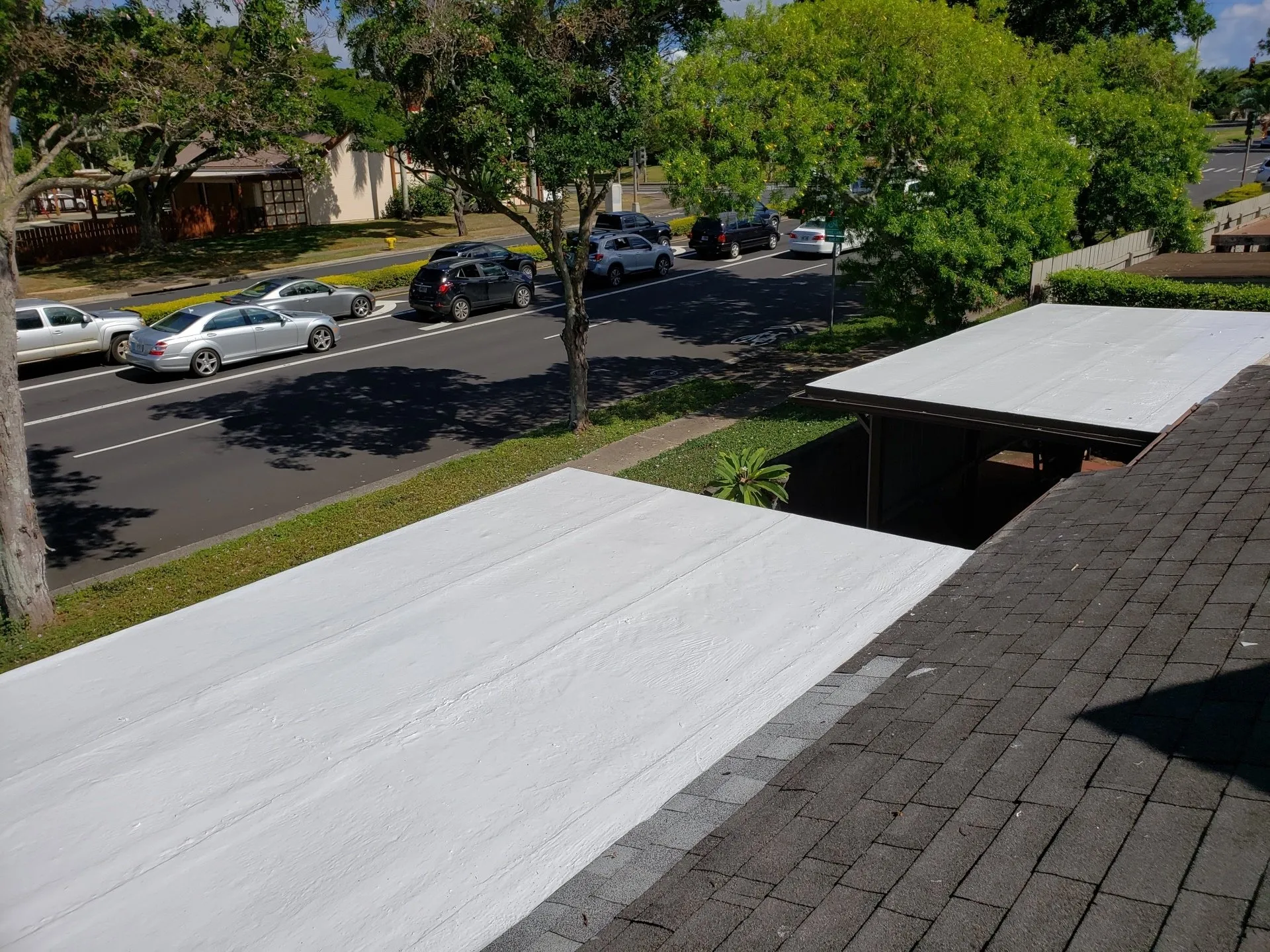A roof with a white roof and a row of cars parked on the side of the road.