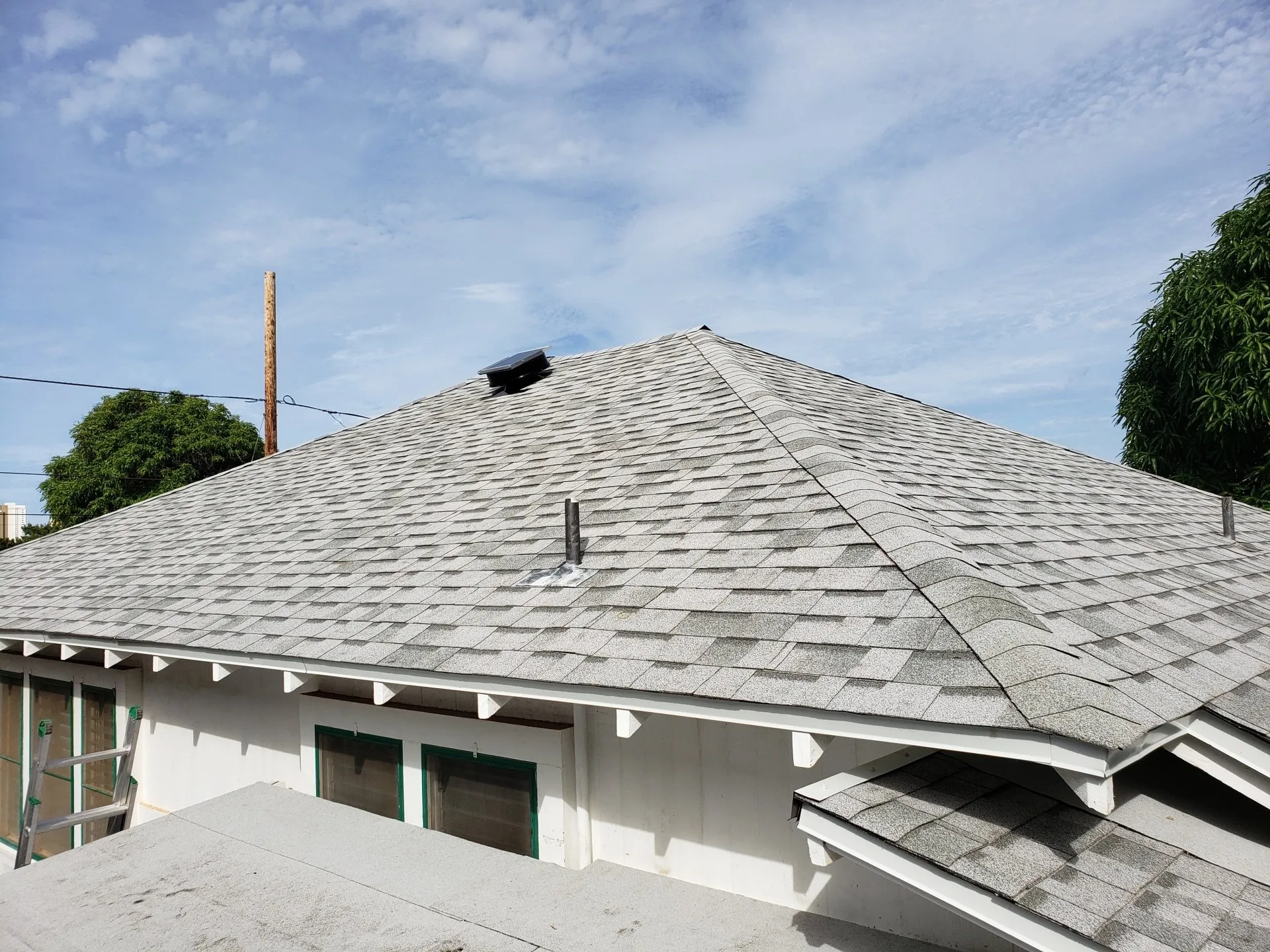 A white house with a gray roof and a chimney on top of it.