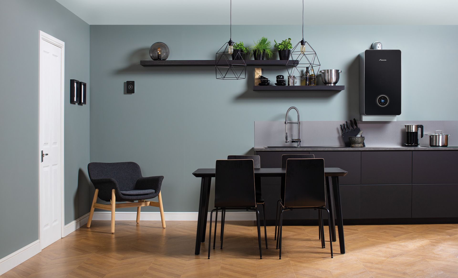 Modern kitchen with dark cabinets, black table and chairs, wall shelf, and wooden floor