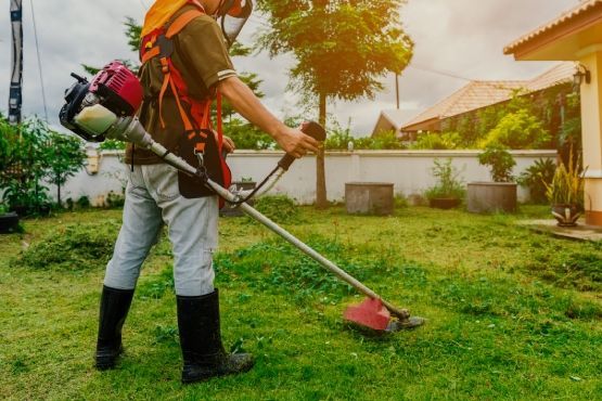 A man is using a lawn mower to cut the grass in a backyard.