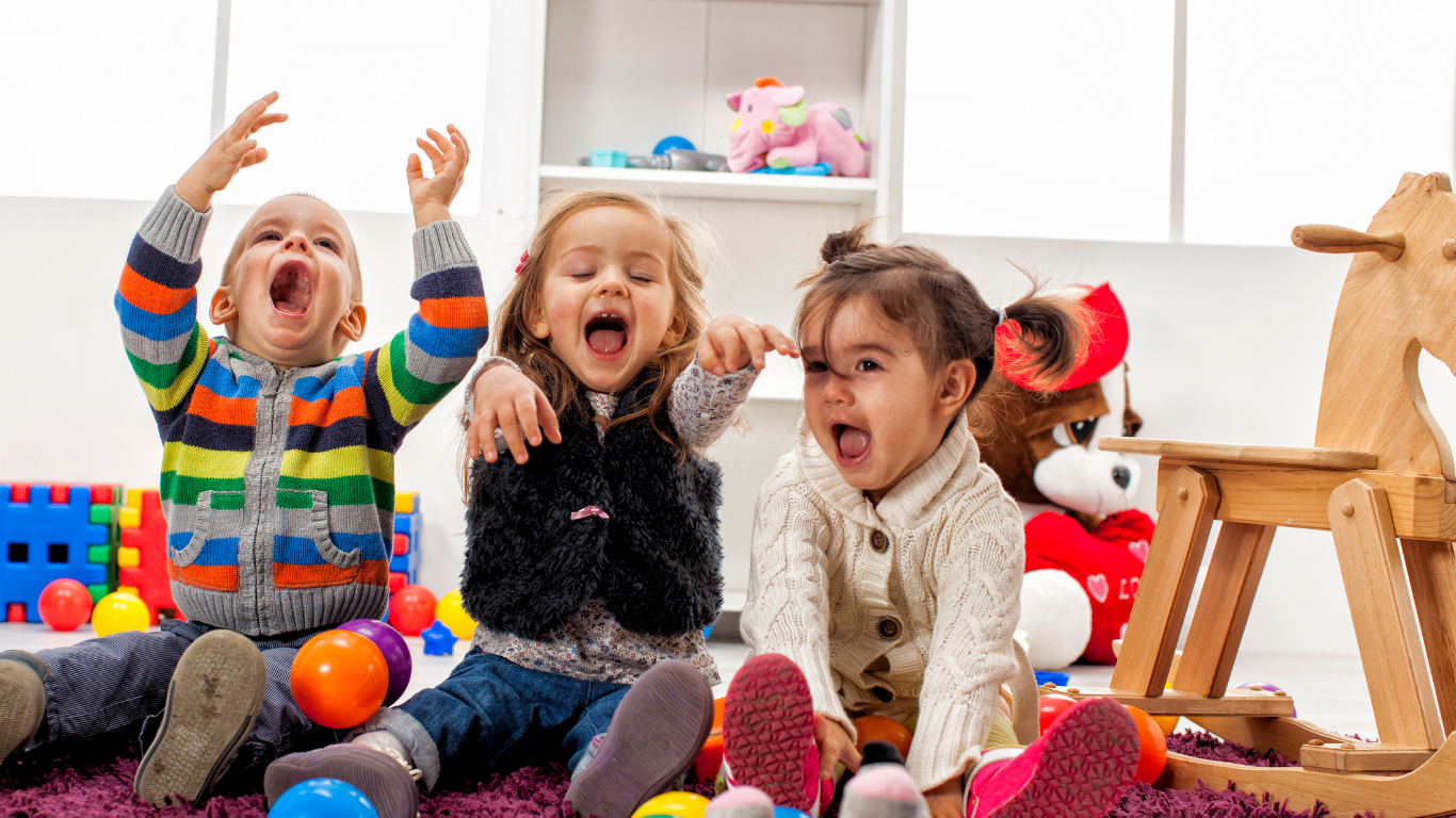 Three children are sitting on the floor playing with toys.