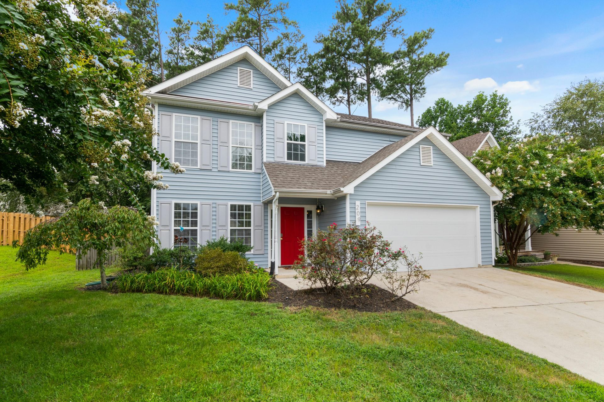 A blue house with a red door and a white garage door.