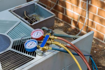 HVAC unit with pressure gauges and attached refrigerant hoses outdoors