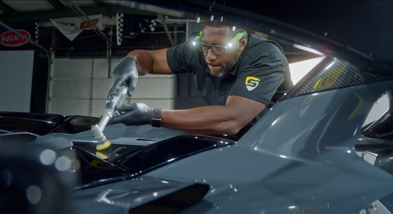 Mechanic cleaning car engine with brush in a garage.