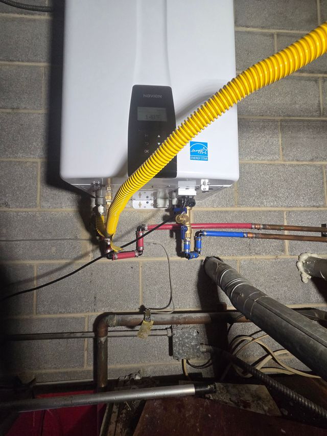 Boiler unit with yellow gas hose and pipes mounted on a cinder block wall