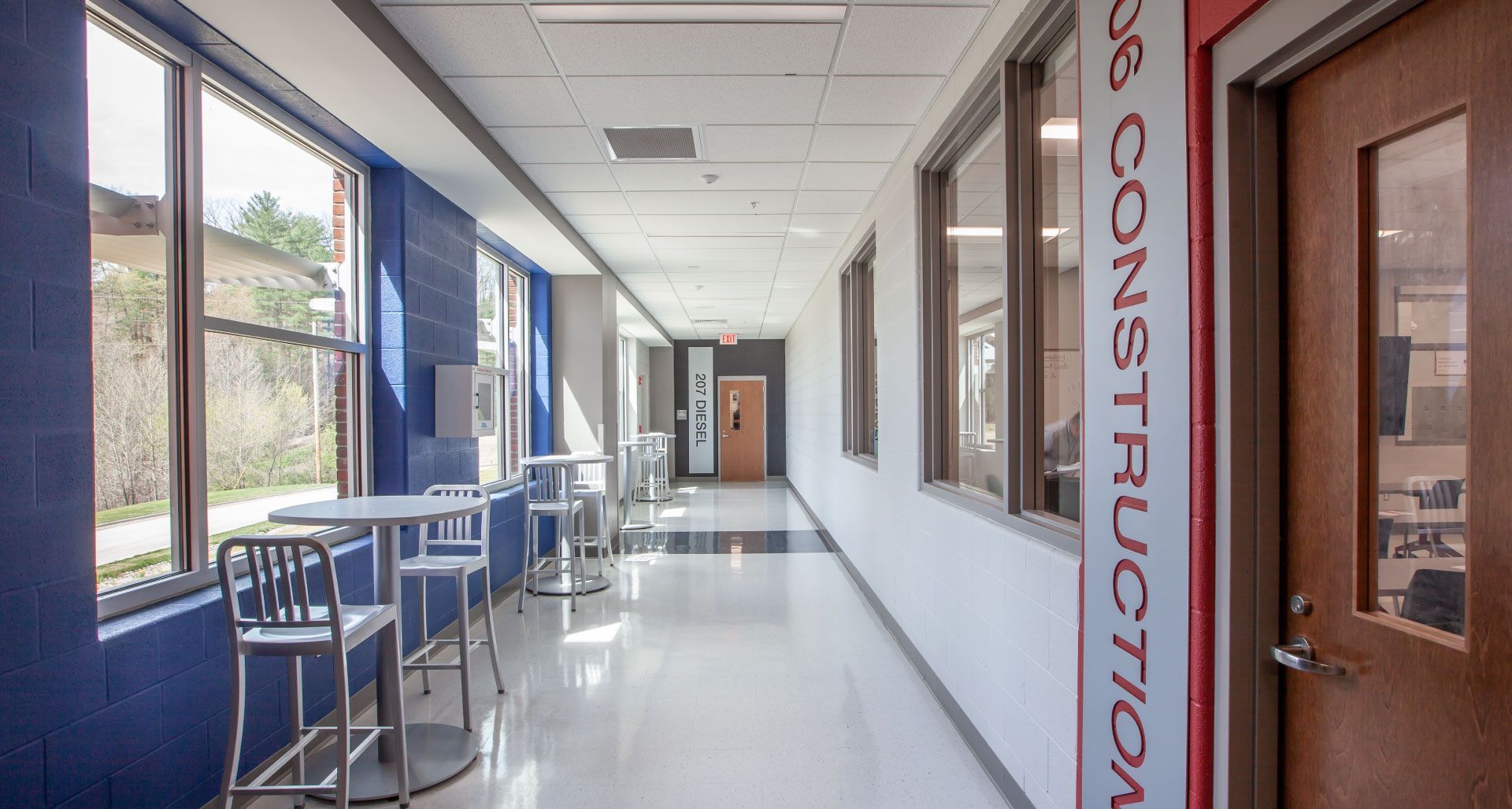 A long hallway with tables and chairs in a building.