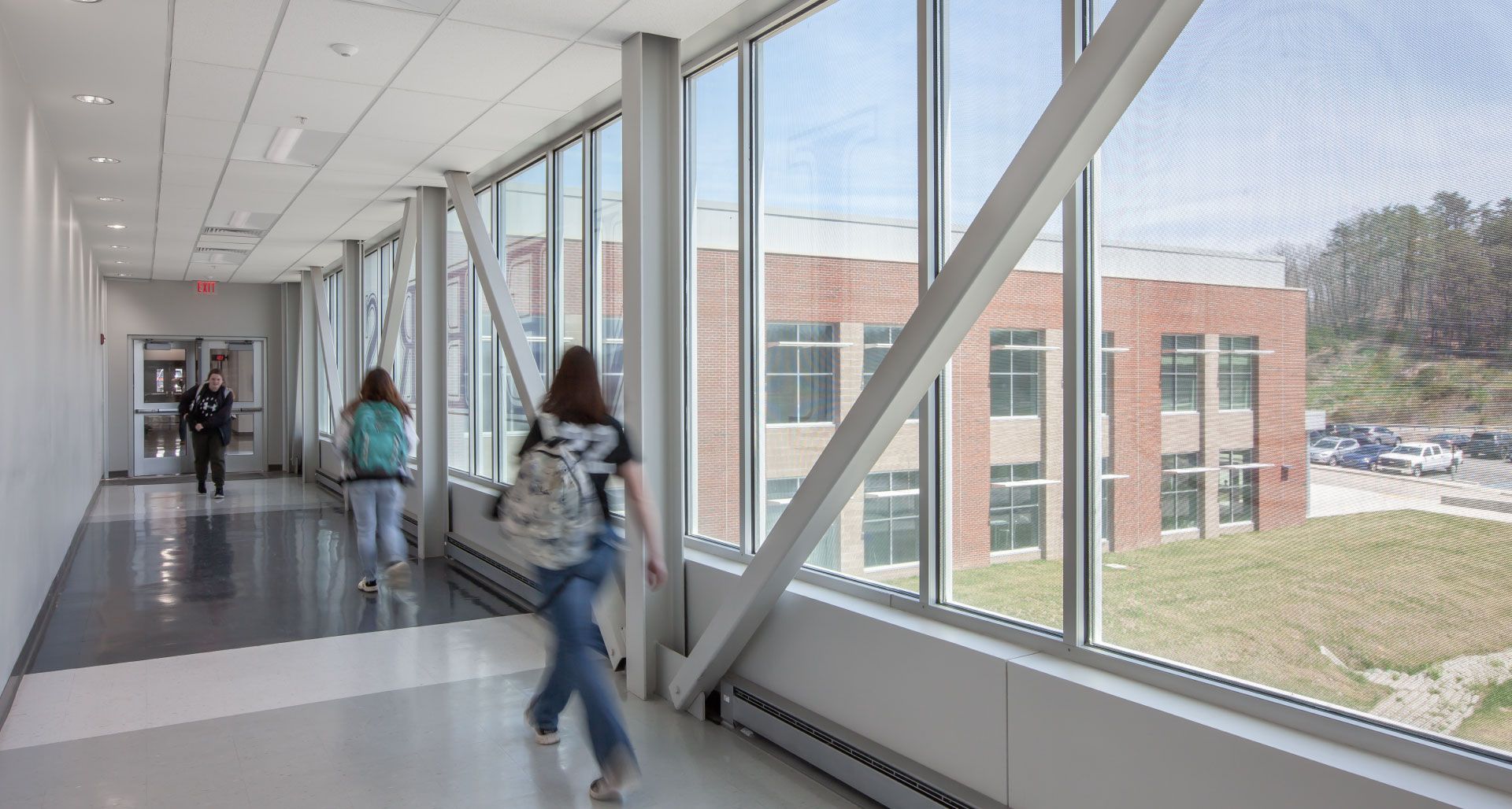 A group of people are walking down a hallway in a school building.