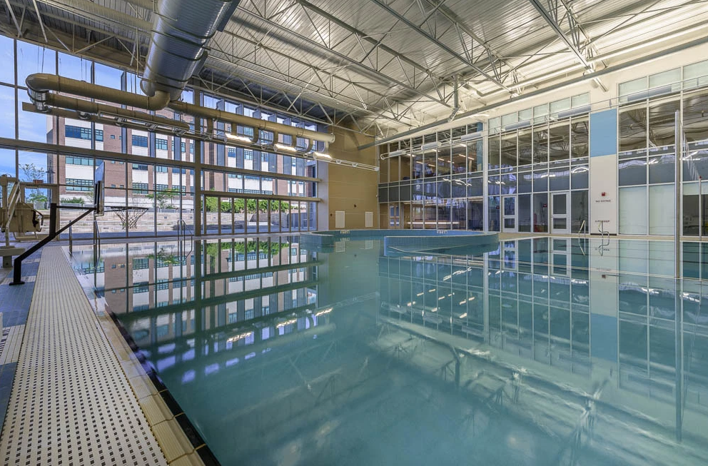 There is a large indoor swimming pool with a lot of windows.