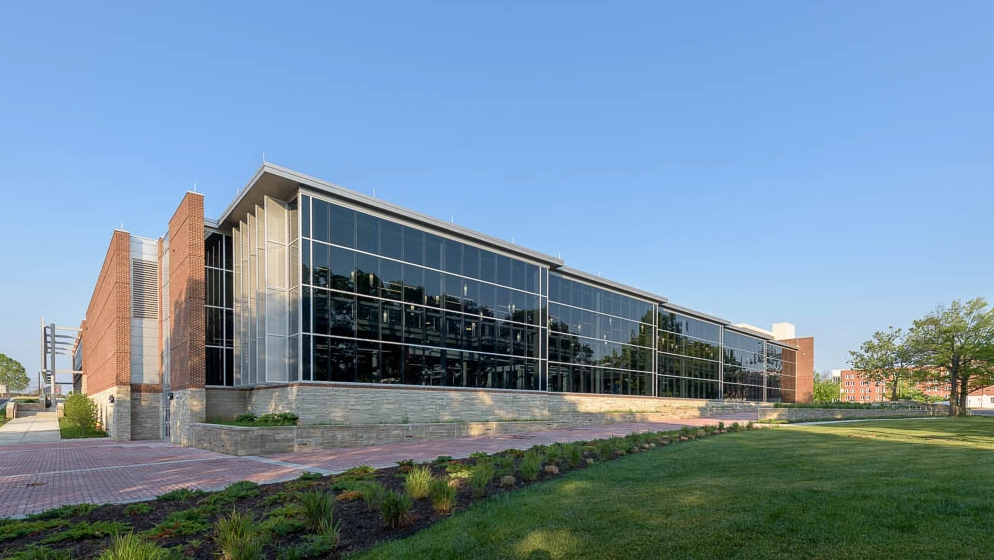 A large building with a lot of windows is sitting on top of a lush green field.