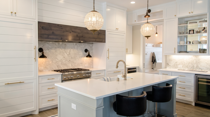 Bright white gourmet kitchen with marble island, pendant lights, and built-in cabinetry