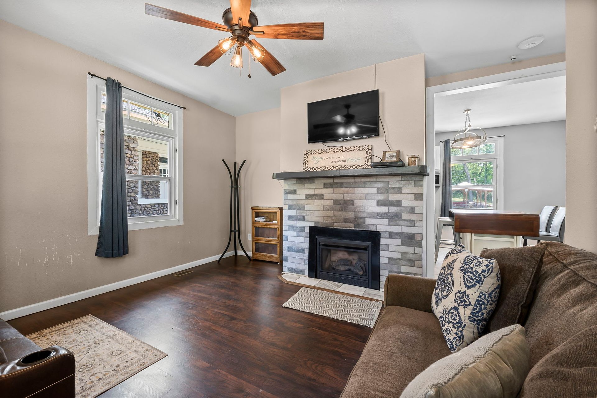 a living room with a couch , fireplace , television and ceiling fan .