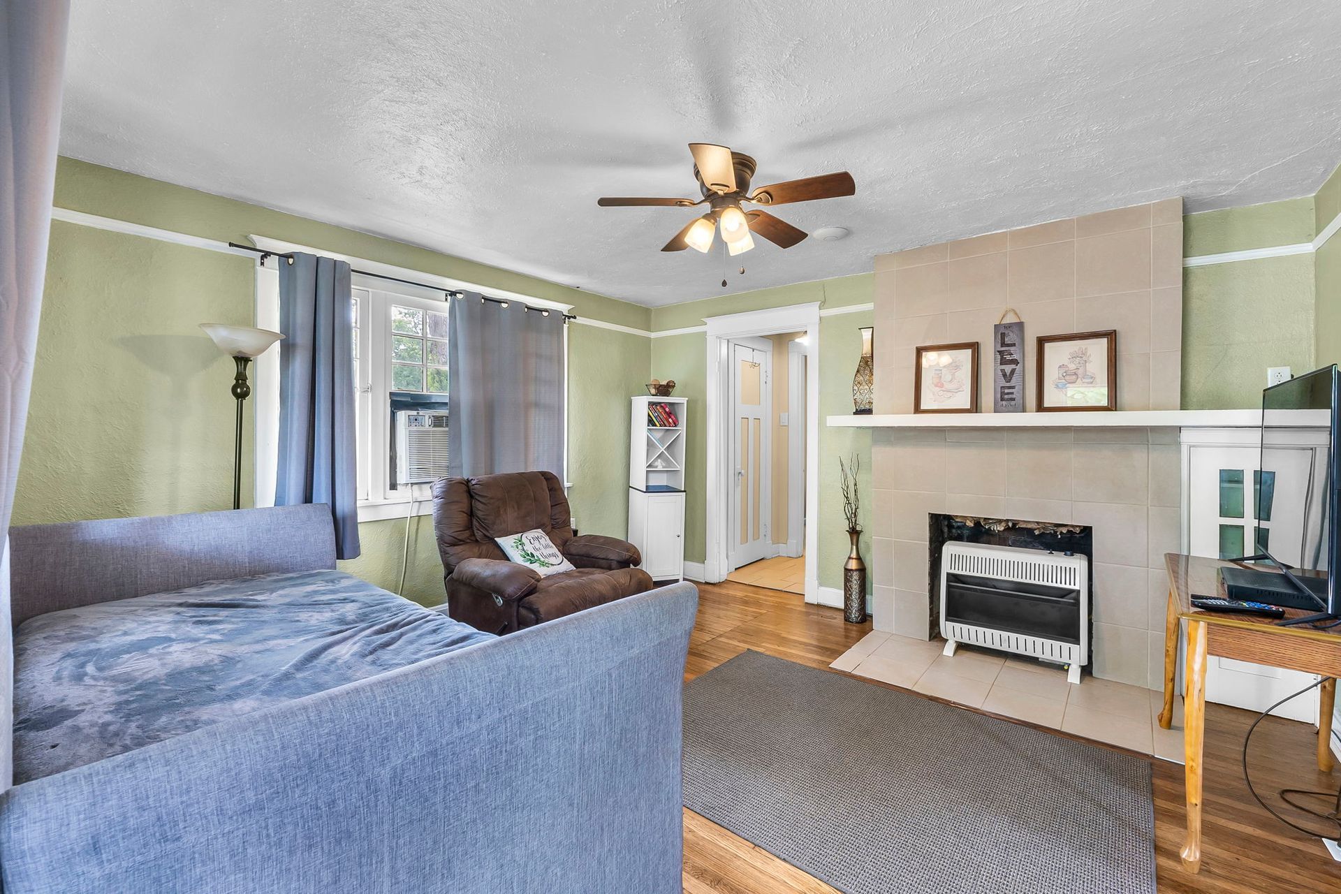 a living room with a couch , chair , fireplace and ceiling fan .