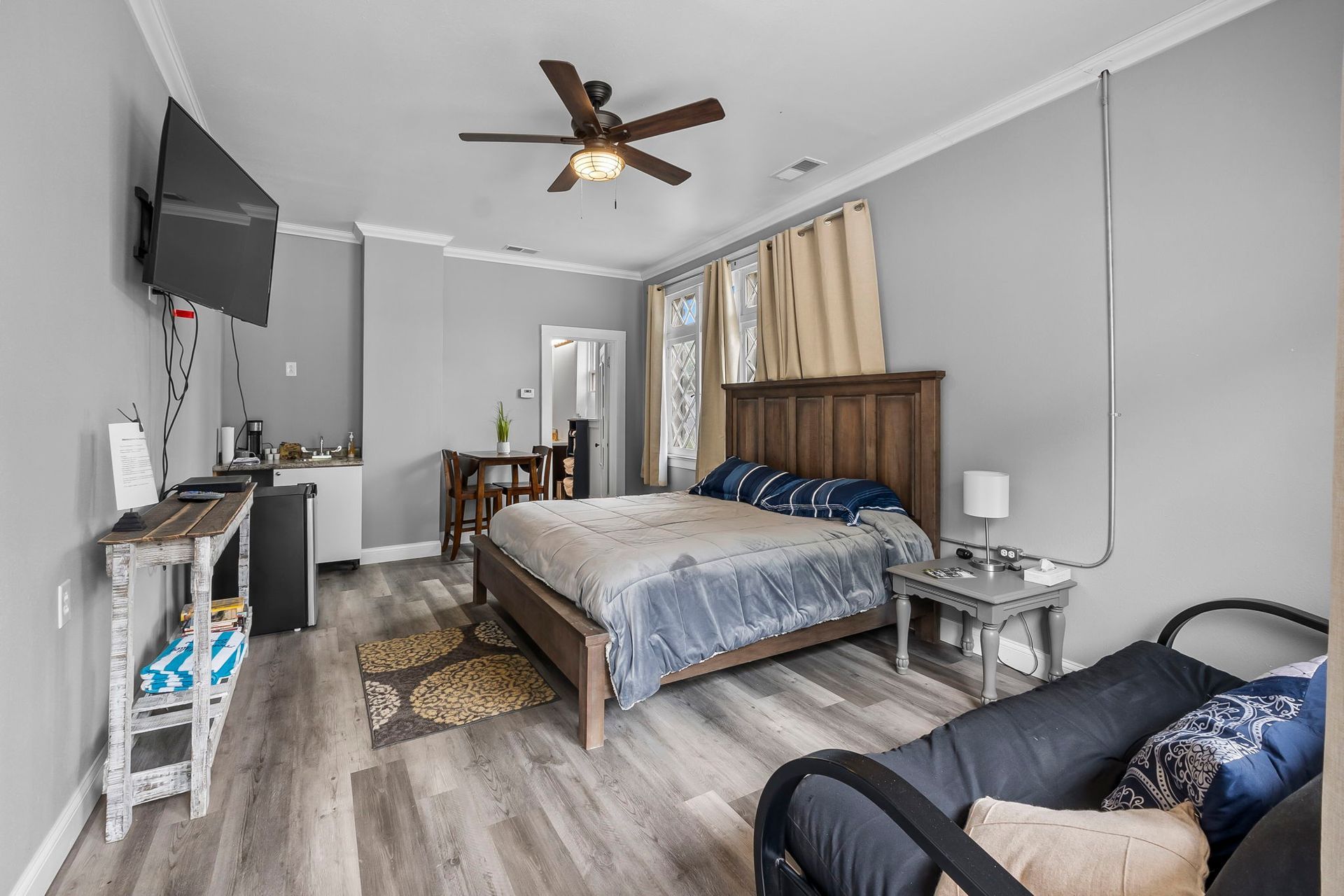 a bedroom with a bed , couch , television and ceiling fan .