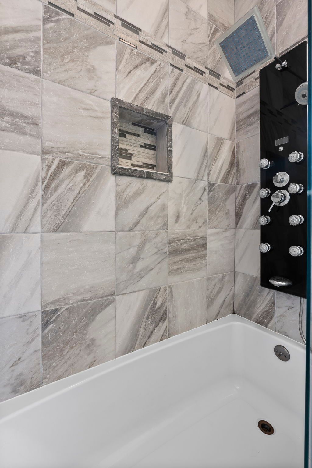 a bathroom with a bathtub , shower , and tiled walls .