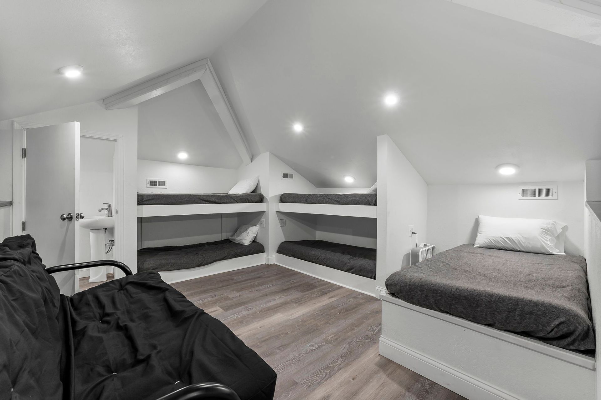 a black and white photo of a bedroom with bunk beds and a couch .