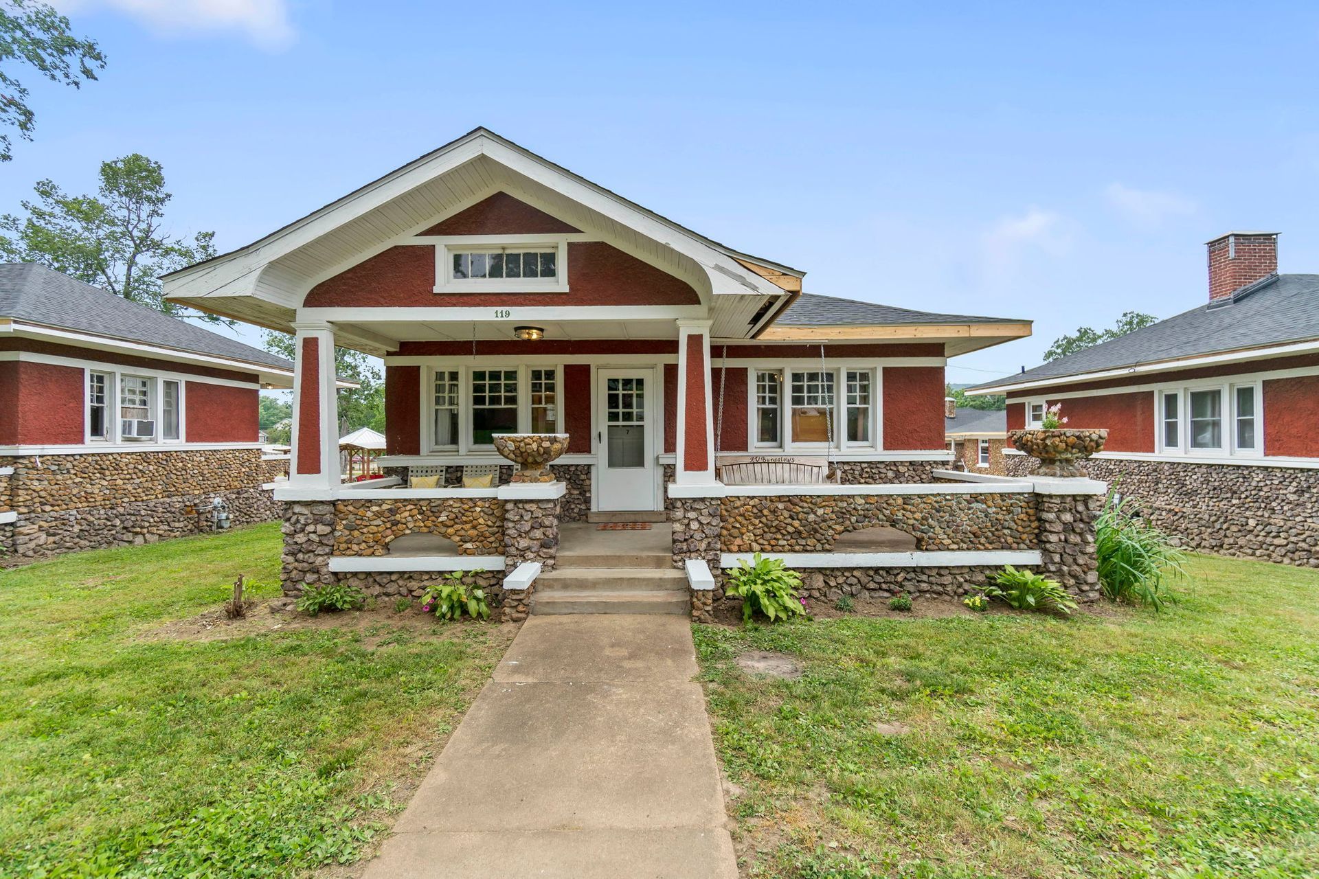 a red house with a stone porch and a walkway leading to it .