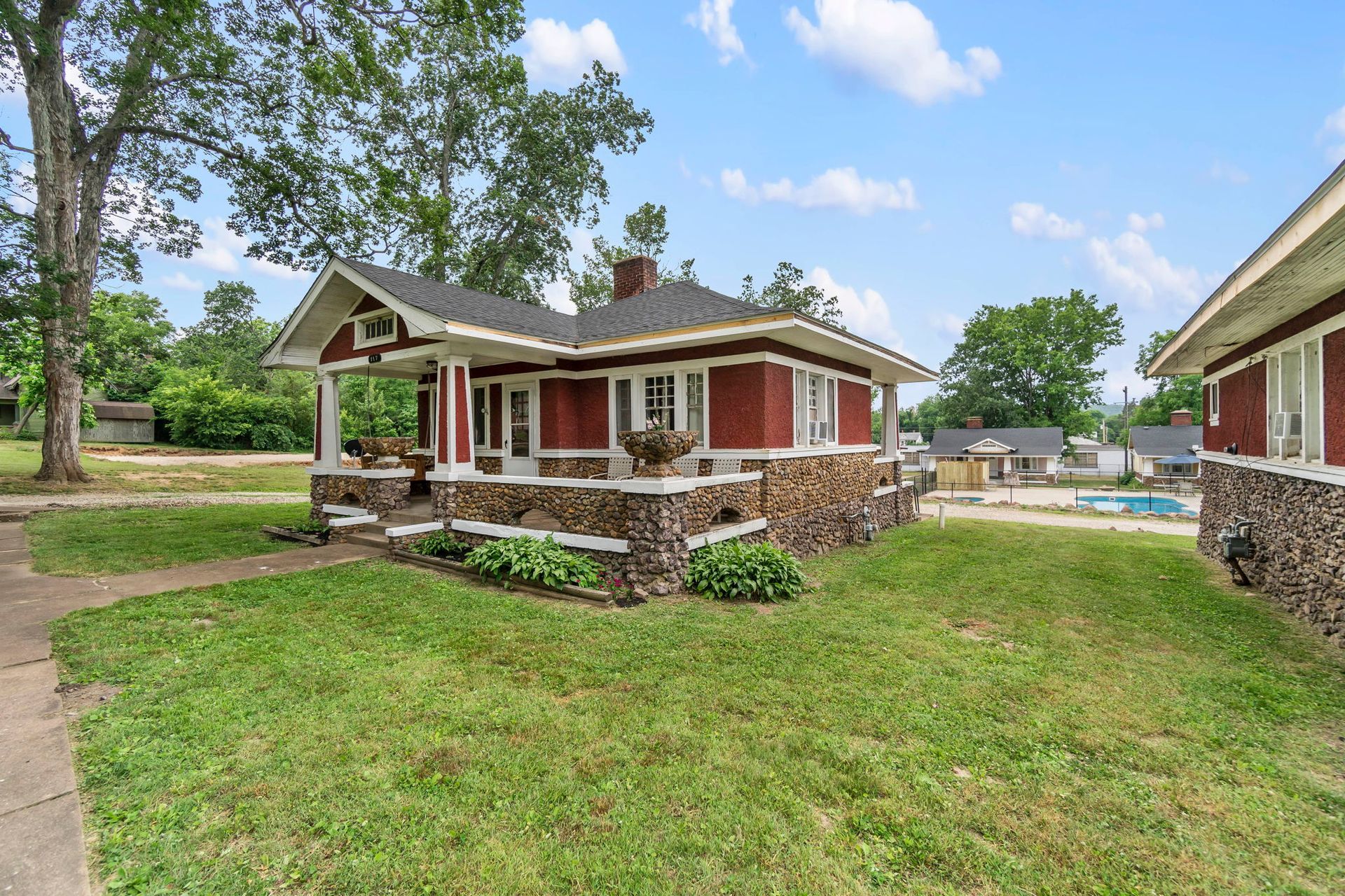 a small red house with a large lawn in front of it .