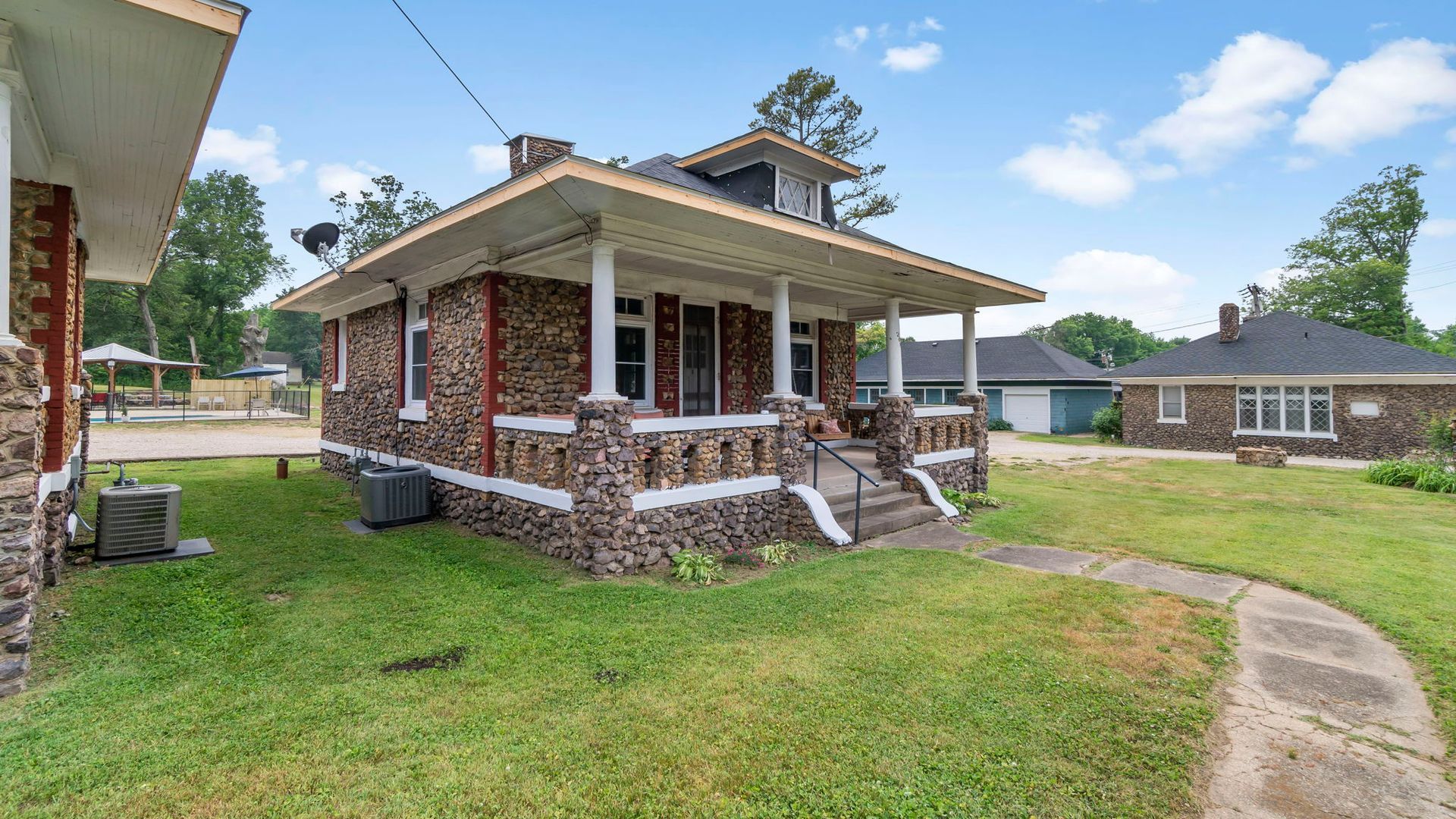 A stone house with a porch and a walkway in front of it.