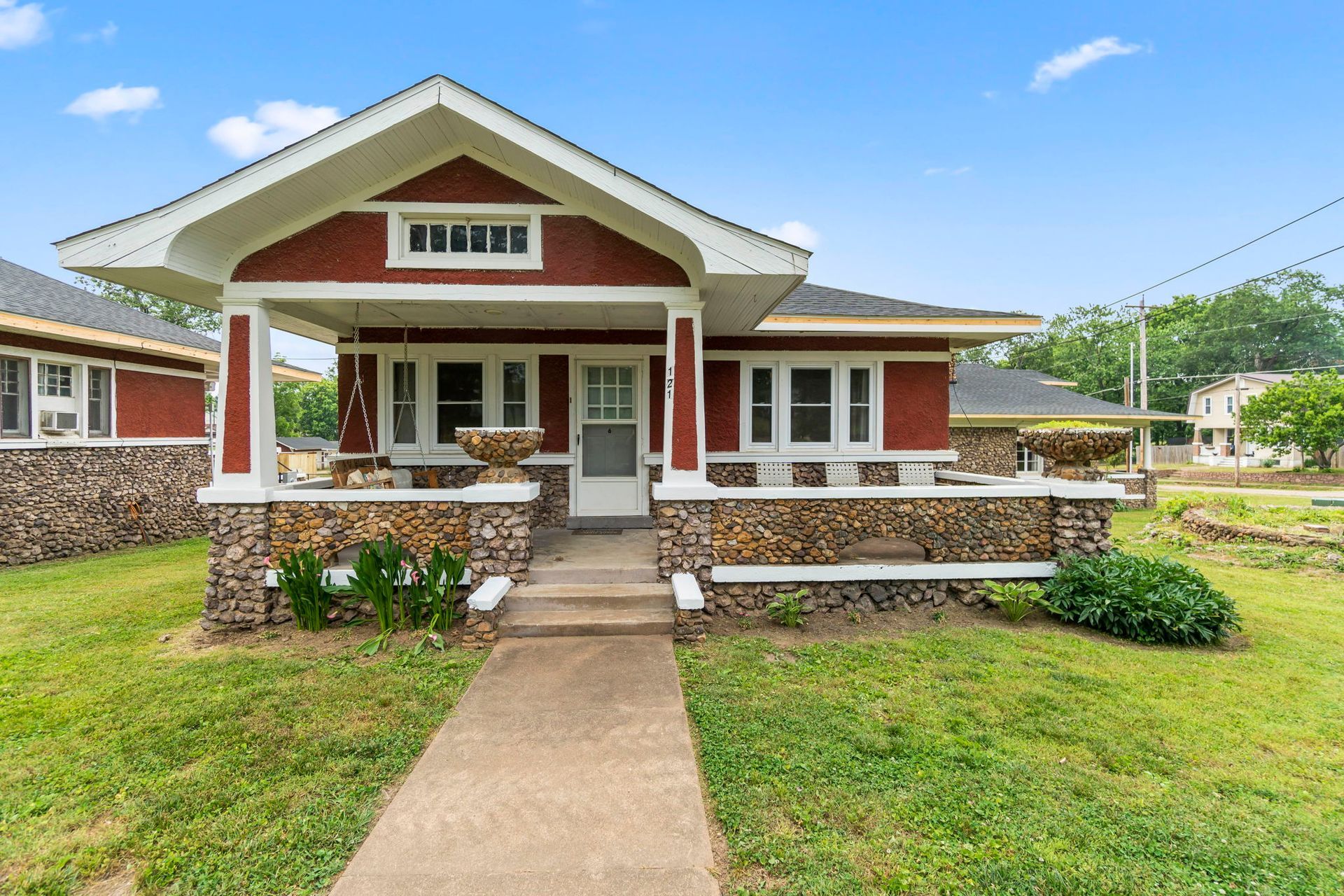 a small red house with a porch and a walkway leading to it .