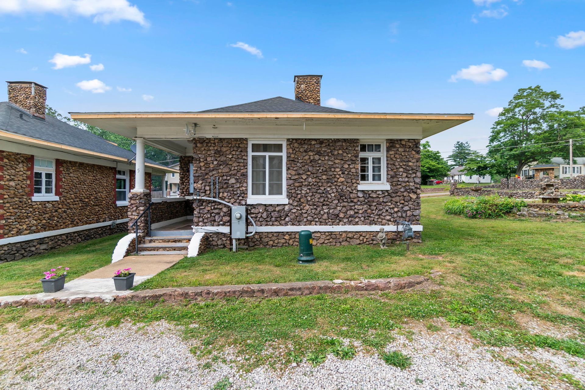 a small brick house is sitting in the middle of a grassy field .