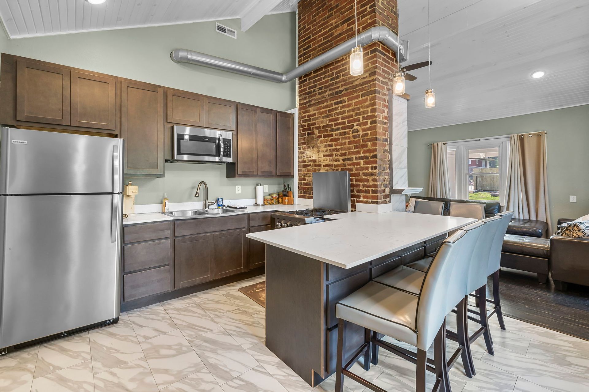 A kitchen with stainless steel appliances , wooden cabinets and a large island.