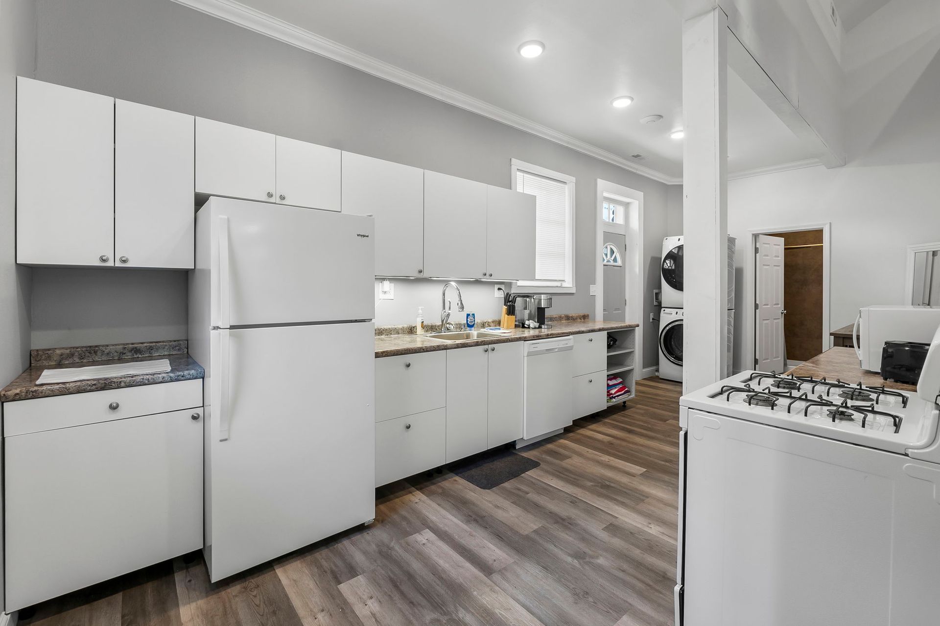 a kitchen with white cabinets , a refrigerator , a stove , and a sink .