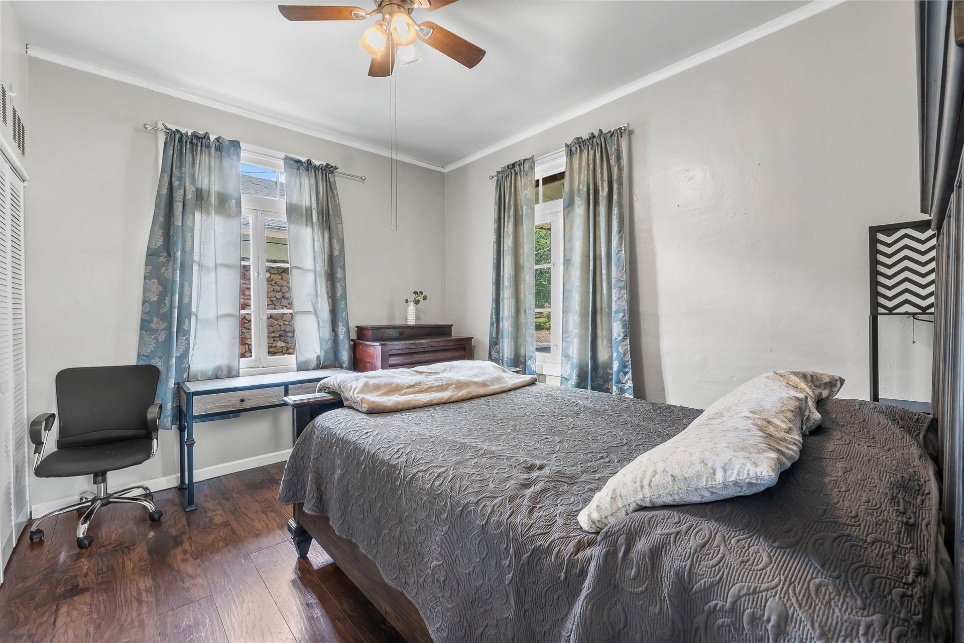 a bedroom with a bed , desk , chair and ceiling fan .