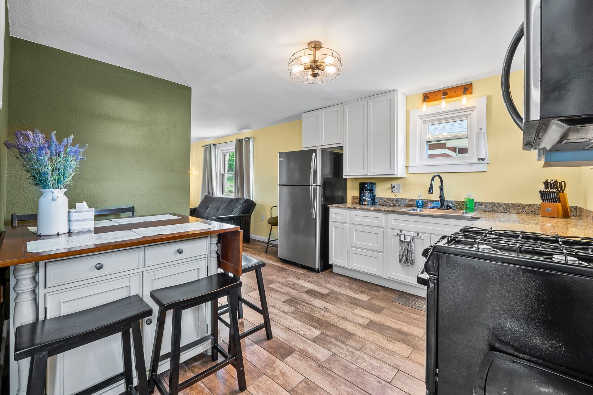 a kitchen with a stove , refrigerator , sink , and stools .