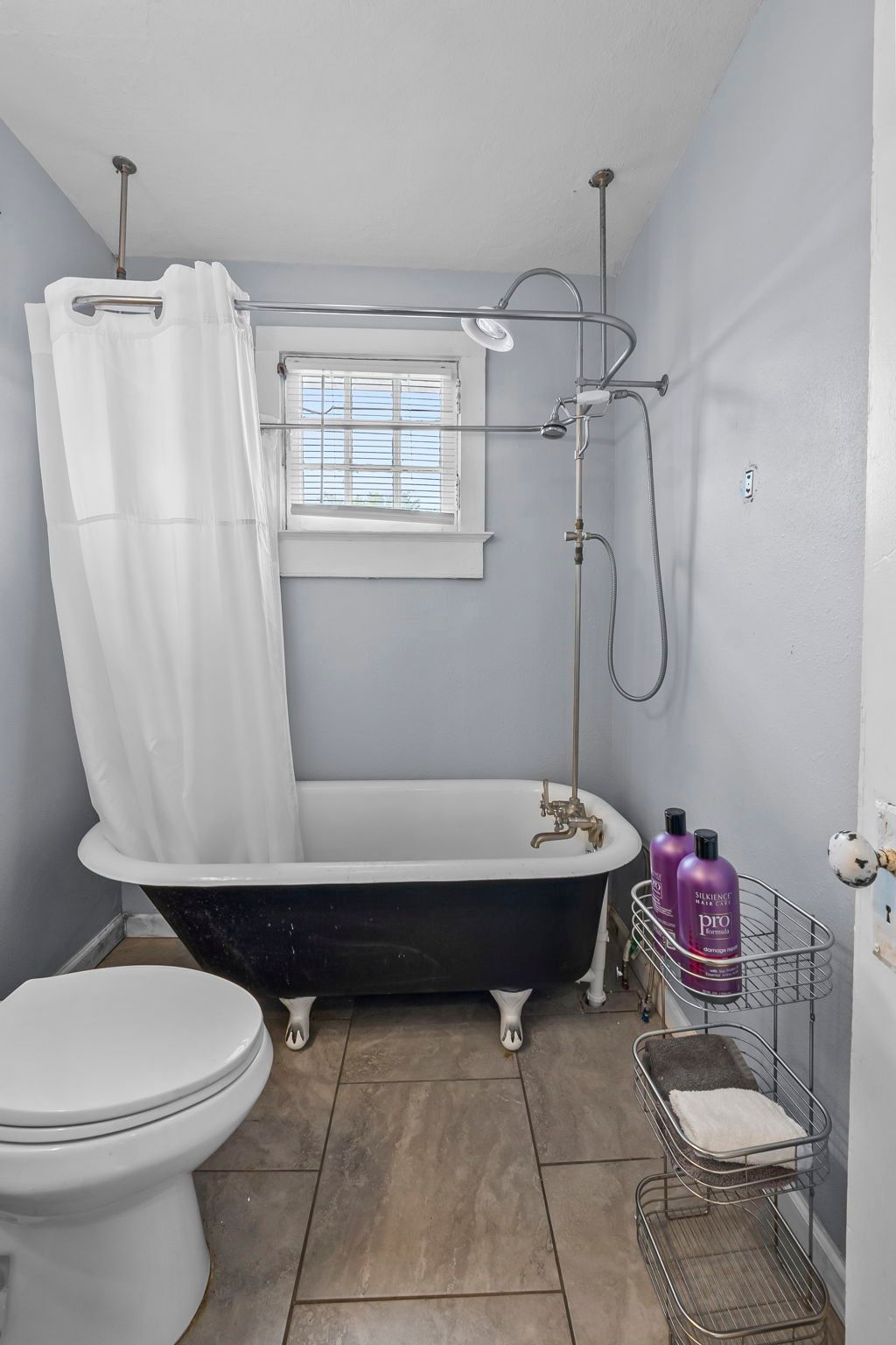 a bathroom with a tub , toilet , shower and window .