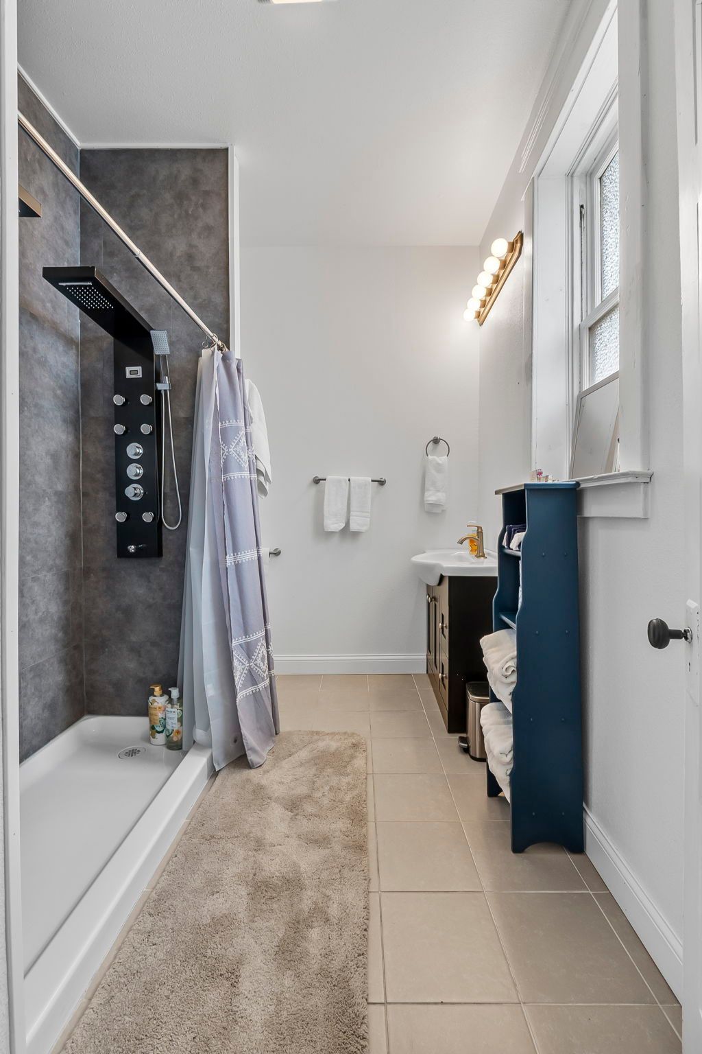 a bathroom with a tub , shower , sink and window .