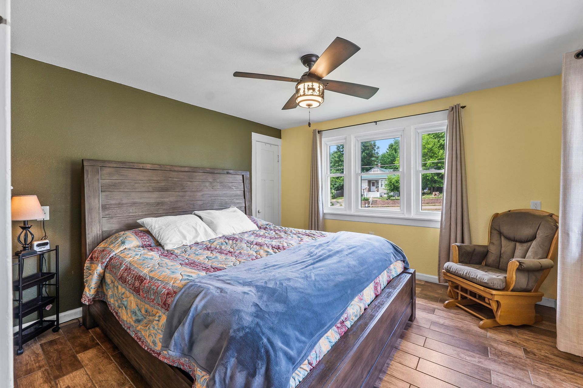 a bedroom with a bed , chair and ceiling fan .