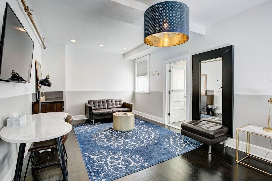 Modern living room with blue rug, white walls, black furniture, and gold accents