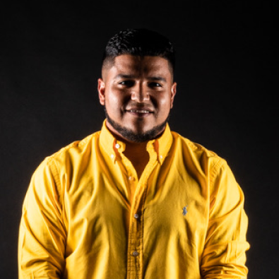 Un hombre que lleva un polo amarillo sonríe para la cámara.
